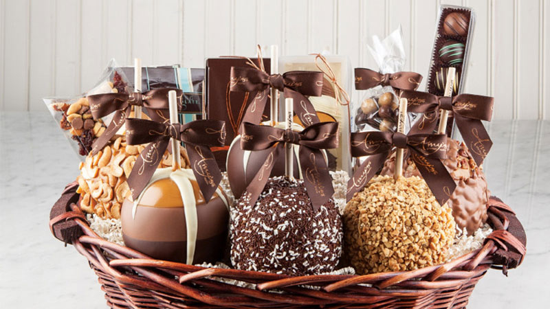 Fancy caramel apples and candies in a woven basket.